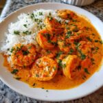 Close-up of a white plate featuring Creamy Cajun Shrimp and Rice, topped with fresh parsley.