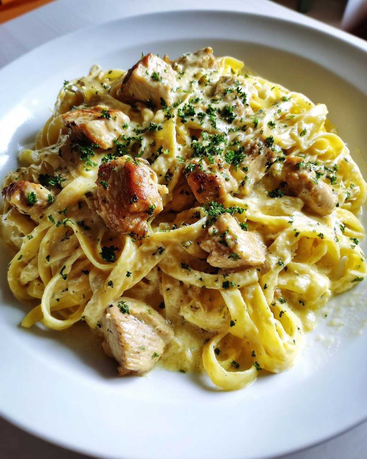 Close-up of rich Creamy Lemon Garlic Pasta with Chicken tossed in a thick sauce and topped with fresh parsley.