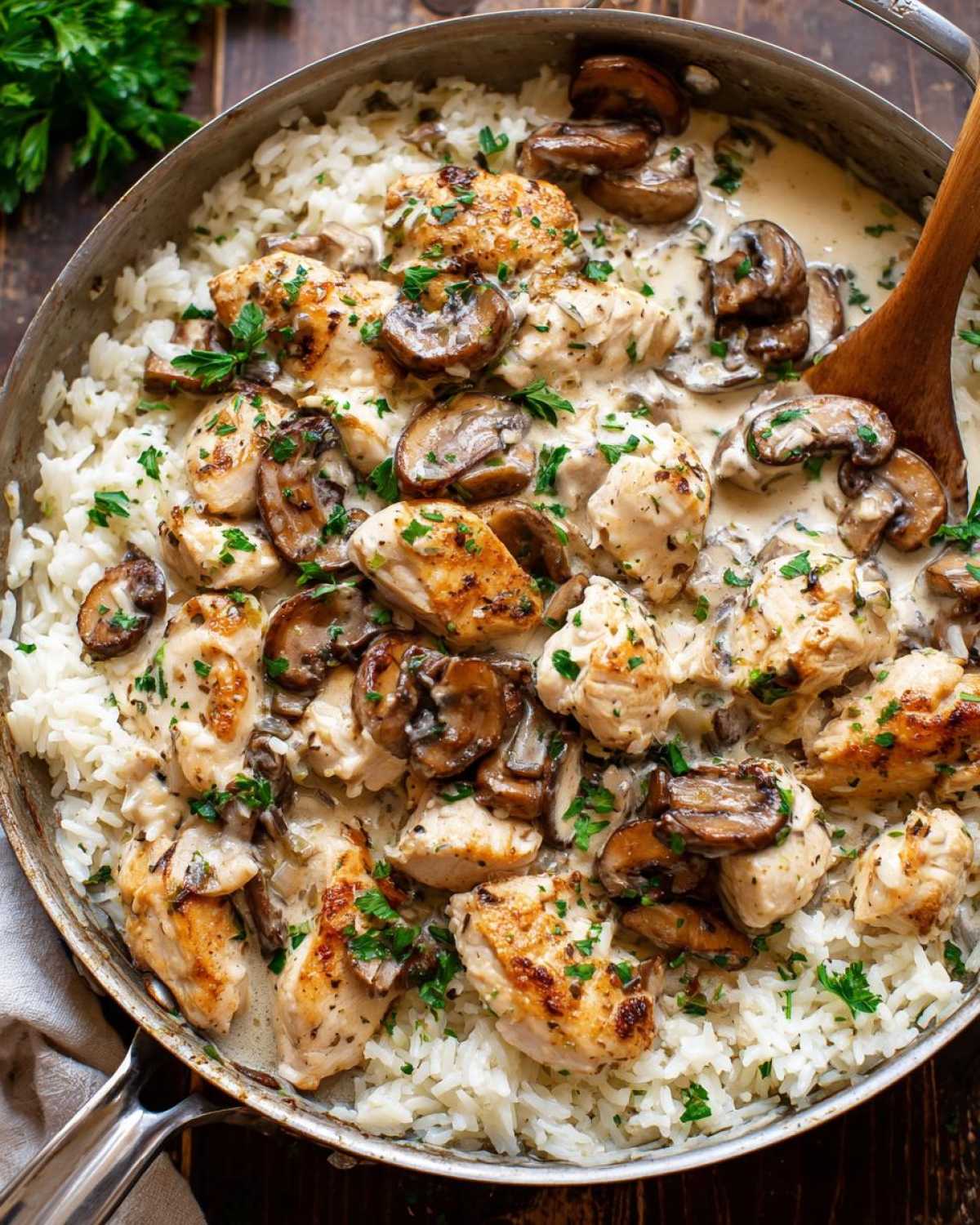 Overhead view of Creamy Mushroom Chicken and Rice Skillet served directly in a metal skillet, topped with fresh parsley.
