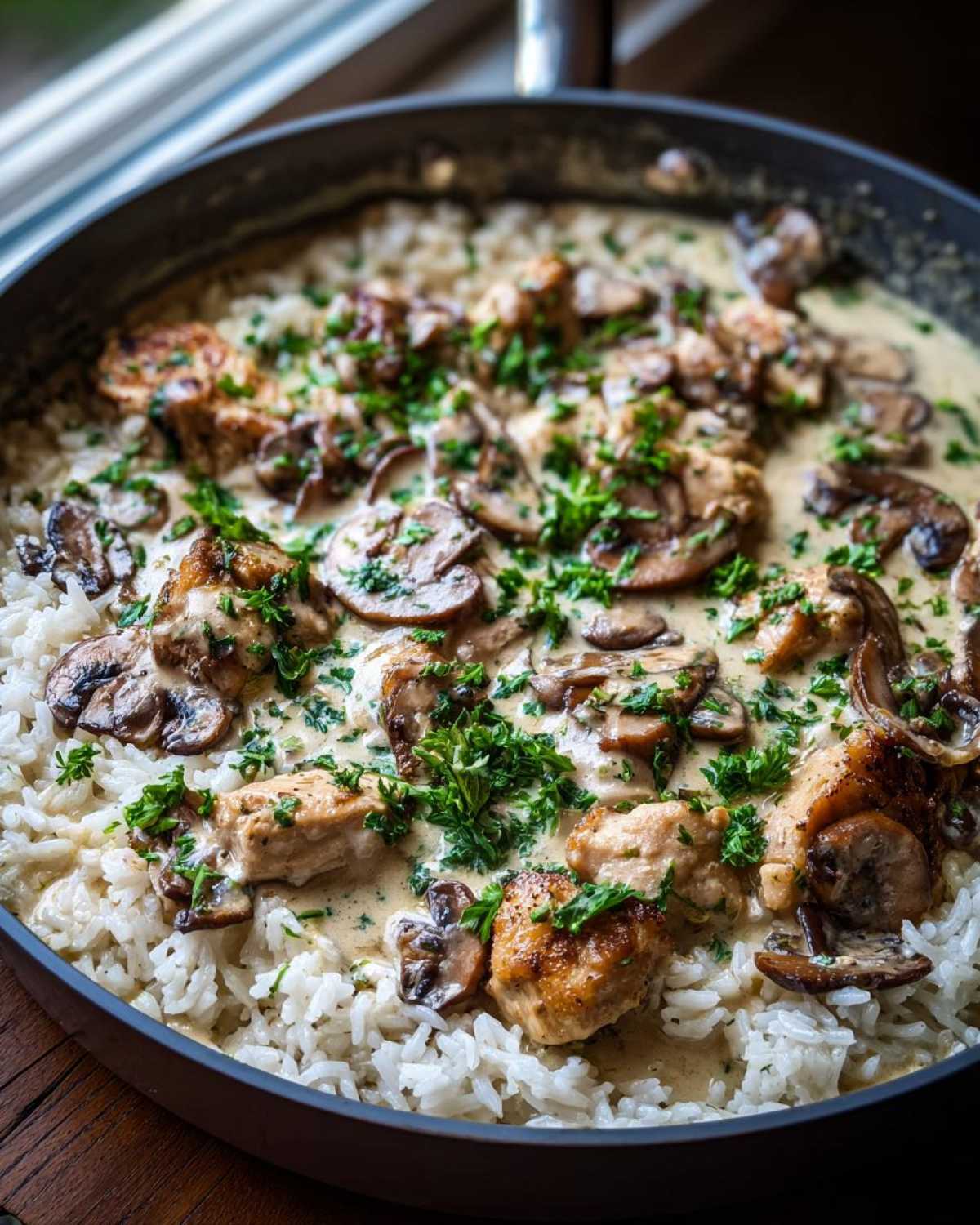 Close-up of Creamy Mushroom Chicken and Rice Skillet garnished with fresh parsley in a dark skillet.