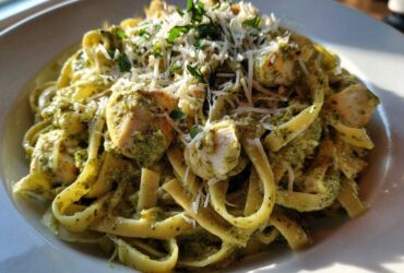 A close-up of rich Creamy Pesto Chicken Pasta with Mozzarella, topped with grated cheese and parsley.