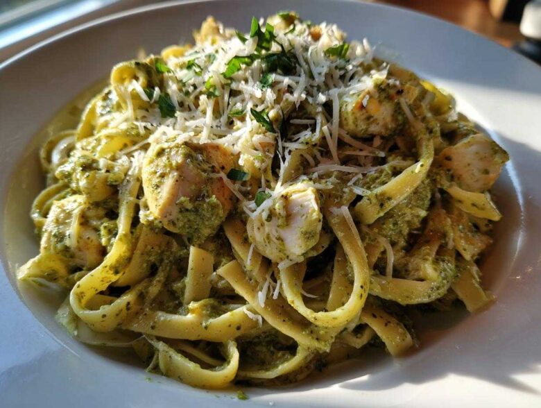 A close-up of rich Creamy Pesto Chicken Pasta with Mozzarella, topped with grated cheese and parsley.