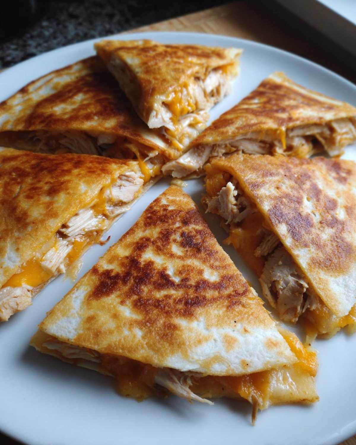 Five crispy, golden-brown slices of Cheesy Chicken Quesadilla with melted cheddar cheese and shredded chicken filling.