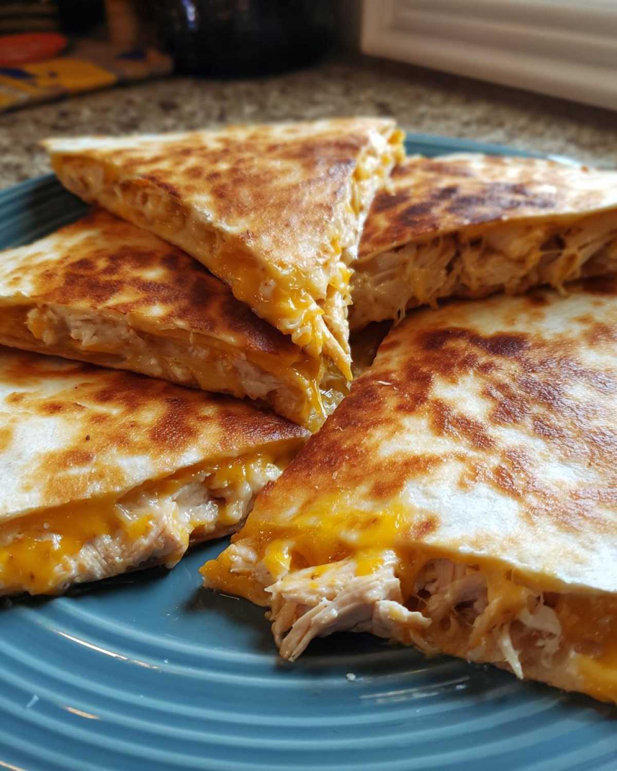 Close-up of crispy golden brown Cheesy Chicken Quesadilla slices showing melted cheese and shredded chicken filling.