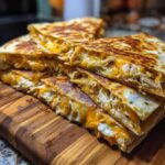 Close-up of stacked, crispy Cheesy Chicken Quesadilla slices showing melted orange and white cheese and shredded chicken.