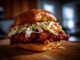 A close-up of a juicy, spicy Crispy Chicken Sandwich topped generously with creamy slaw on a brioche bun.