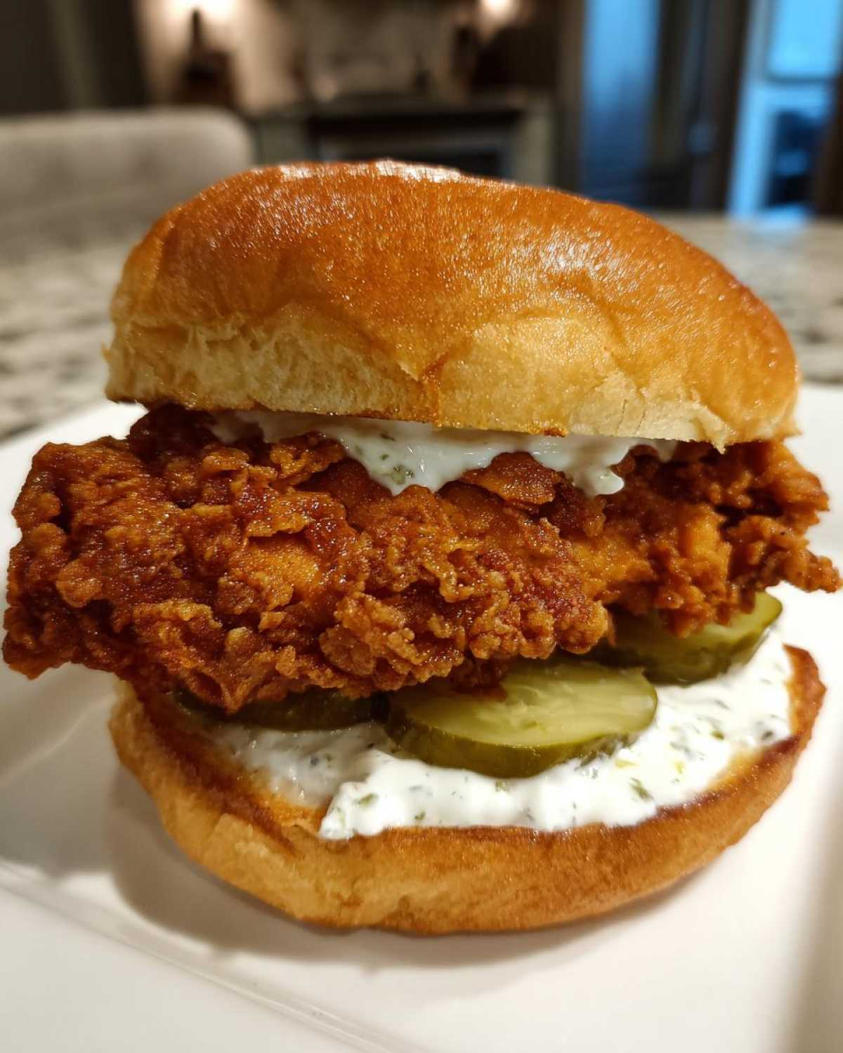 A close-up of a juicy Crispy Chicken Sandwich with Garlic Sauce, pickles, and a toasted brioche bun.