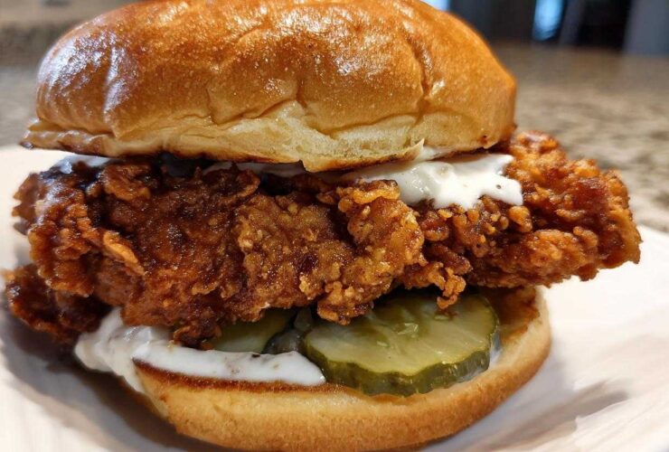 A close-up of a Crispy Chicken Sandwich with Garlic Sauce, featuring a thick fried chicken patty, pickles, and a brioche bun.