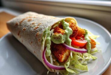 A delicious Crispy Chicken Wrap with Avocado Sauce, filled with crispy chicken, lettuce, red onion, and tomato.