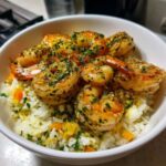 Close-up of a white bowl filled with Garlic Butter Shrimp Bowl with Rice, topped with parsley.