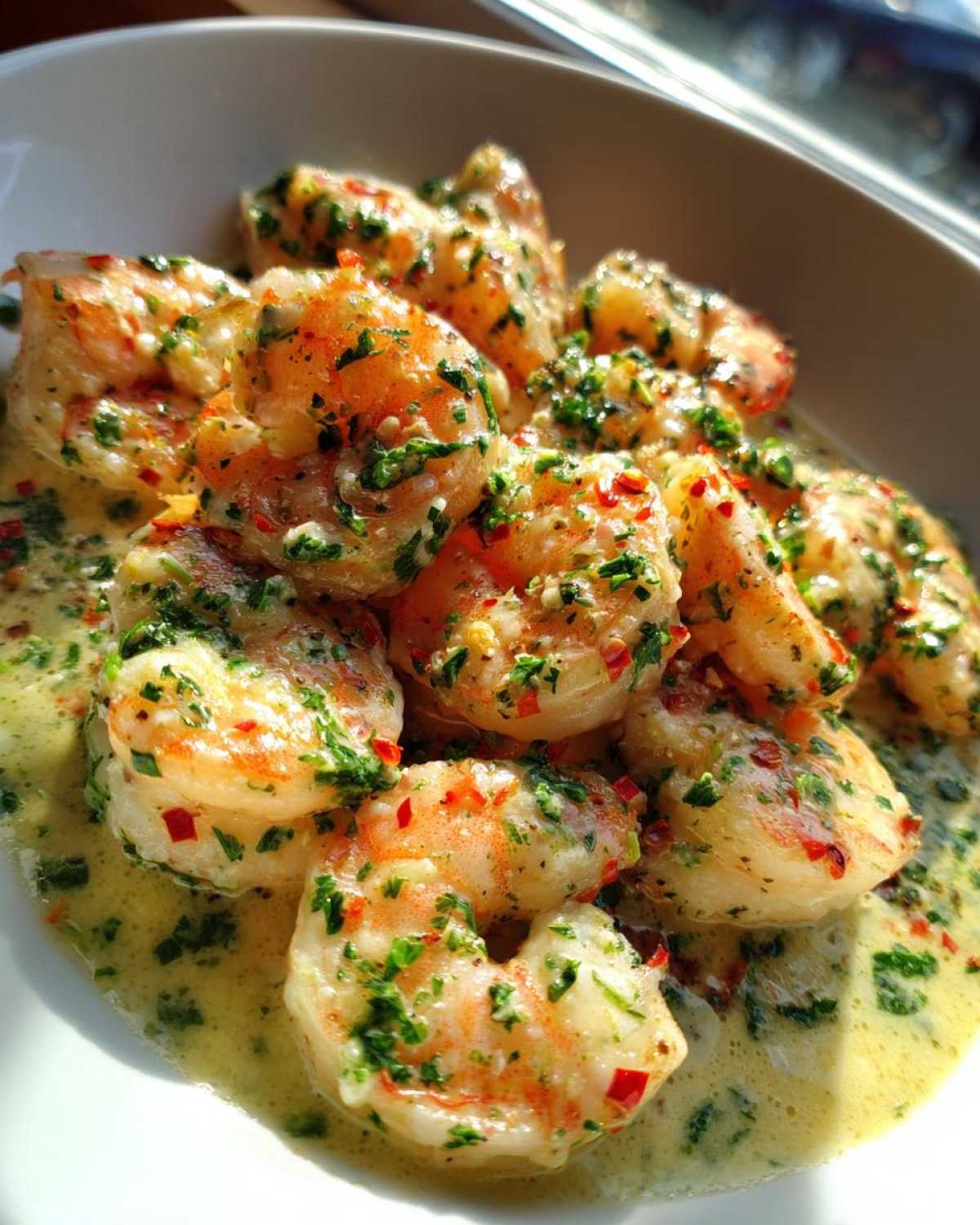 Close-up of plump shrimp coated in a rich Garlic Butter Shrimp with Creamy Parmesan Sauce, garnished with parsley and red pepper flakes.