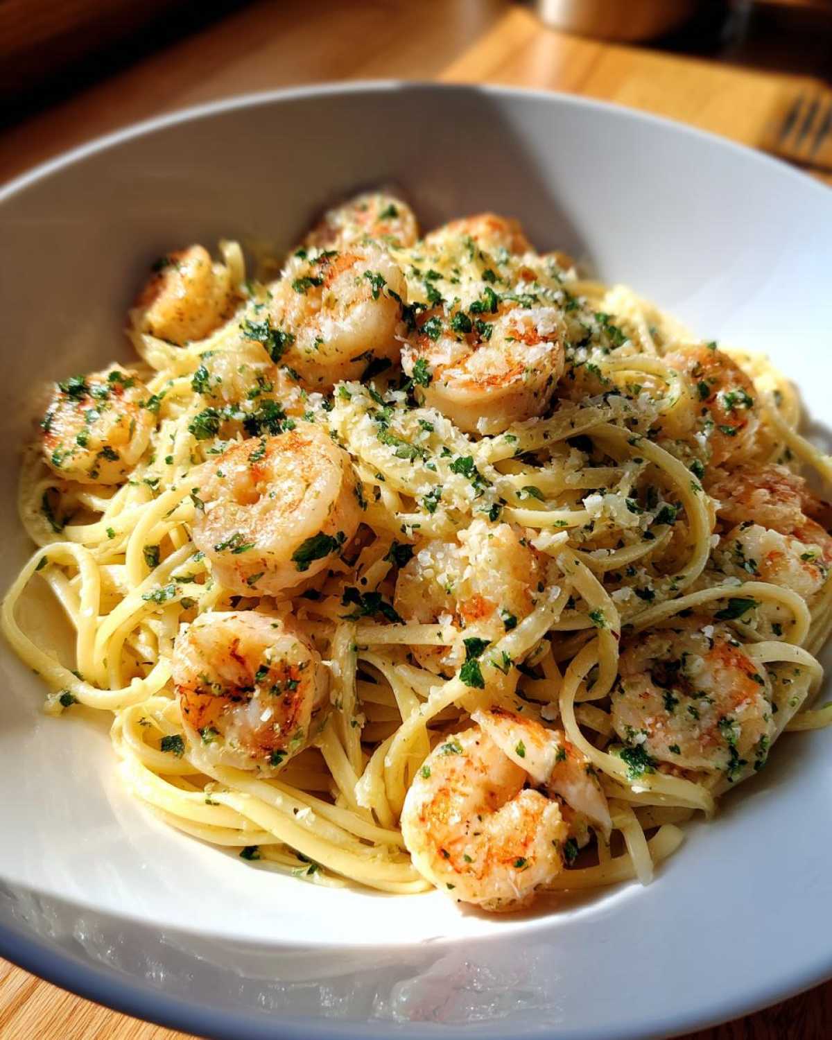 A close-up of Garlic Butter Shrimp Pasta with Cream Sauce, topped with parmesan and parsley, served in a white bowl.