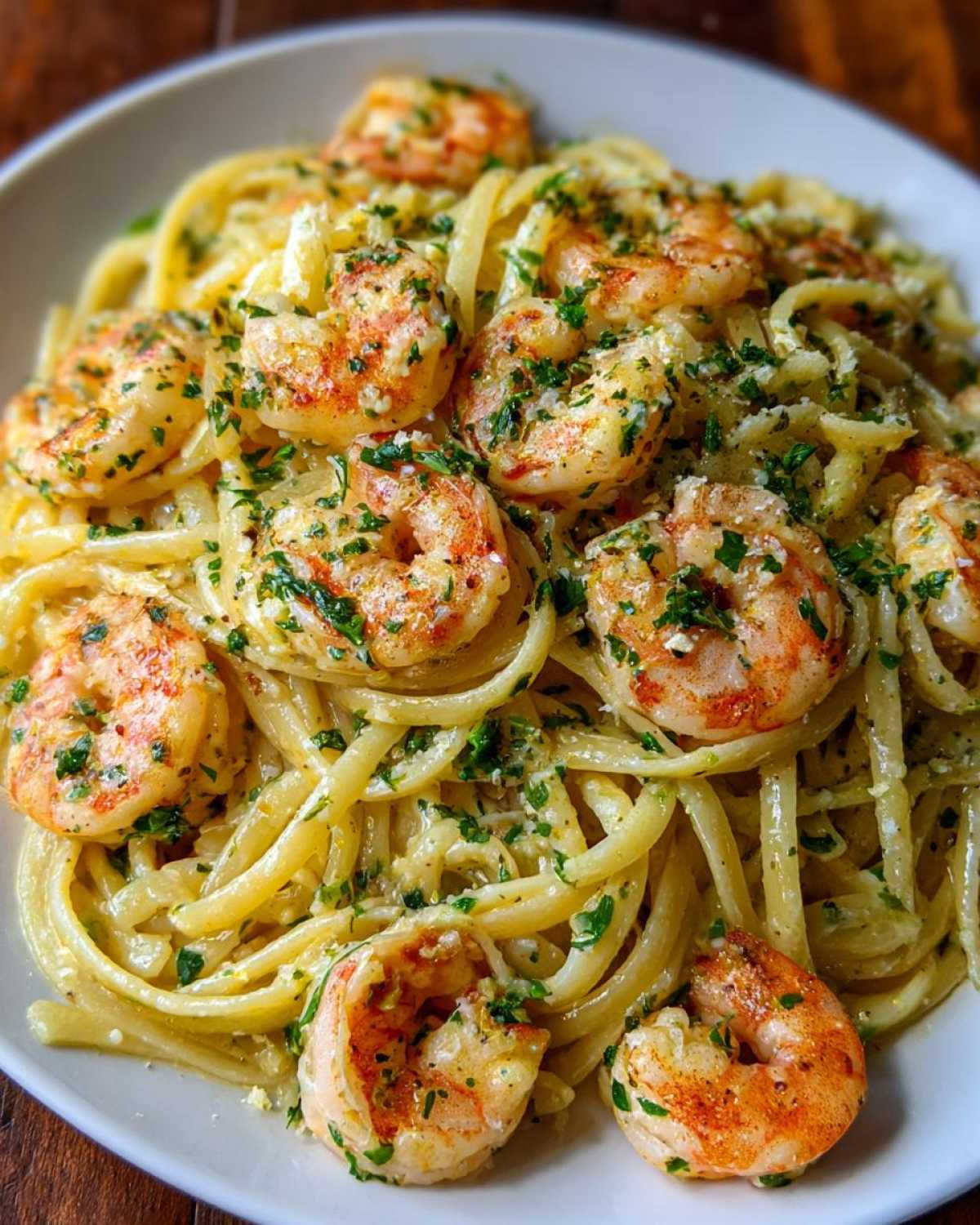 A close-up shot of a white bowl filled with Garlic Butter Shrimp Pasta with Cream Sauce, topped with parsley.