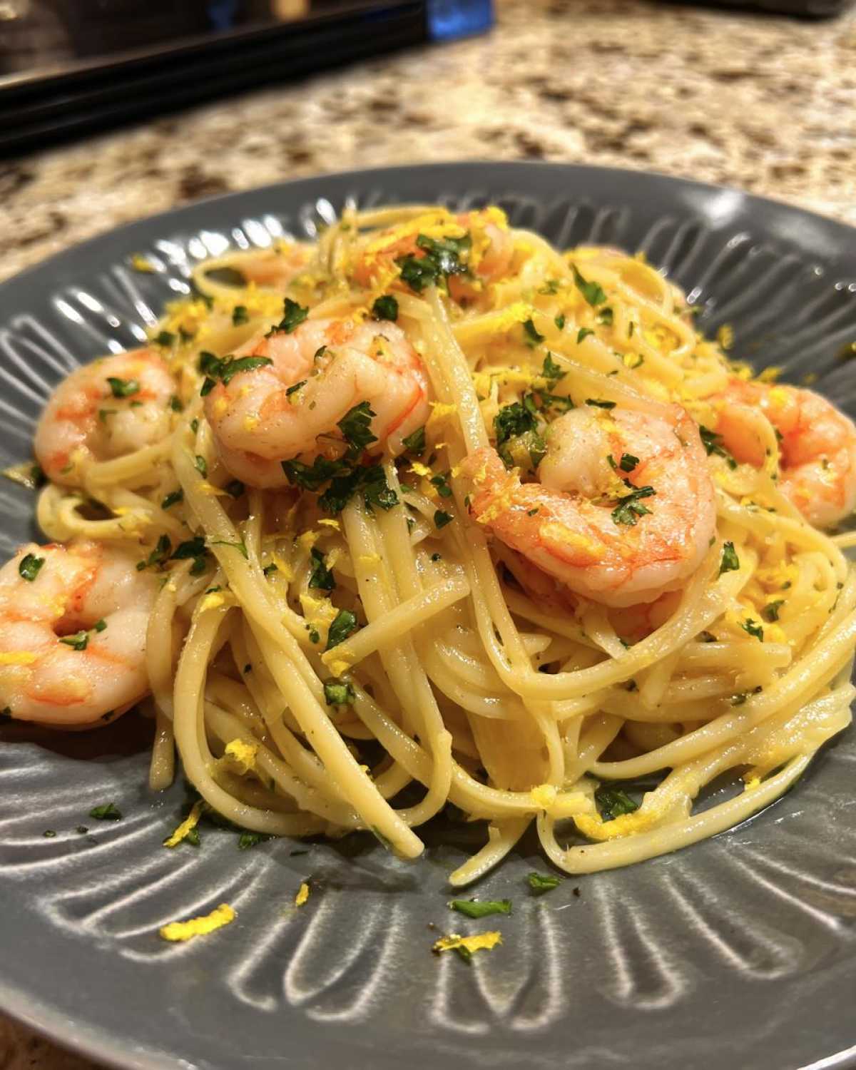 Close-up of Garlic Butter Shrimp Pasta with Lemon Flavor, featuring linguine, pink shrimp, and bright yellow lemon zest.