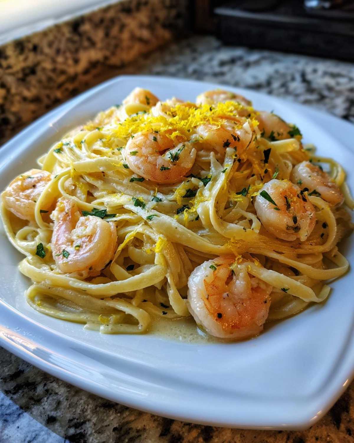 A plate of Garlic Butter Shrimp Pasta with Lemon Flavor, topped generously with bright yellow lemon zest and parsley.