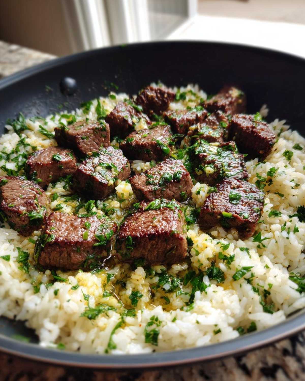 Close-up of Garlic Butter Steak and Rice Skillet Dinner featuring seared steak bites over white rice, drizzled with garlic butter and fresh parsley.