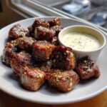 A plate of perfectly seared Garlic Butter Steak Bites topped with minced garlic, served with a side of creamy garlic sauce.