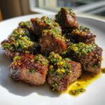 Close-up of perfectly seared Garlic Butter Steak Bites generously topped with a vibrant green herb sauce.