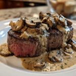 A perfectly cooked medium-rare steak topped with creamy mushroom sauce and sliced mushrooms, featuring Garlic Butter Steak with Creamy Mushroom Sauce.