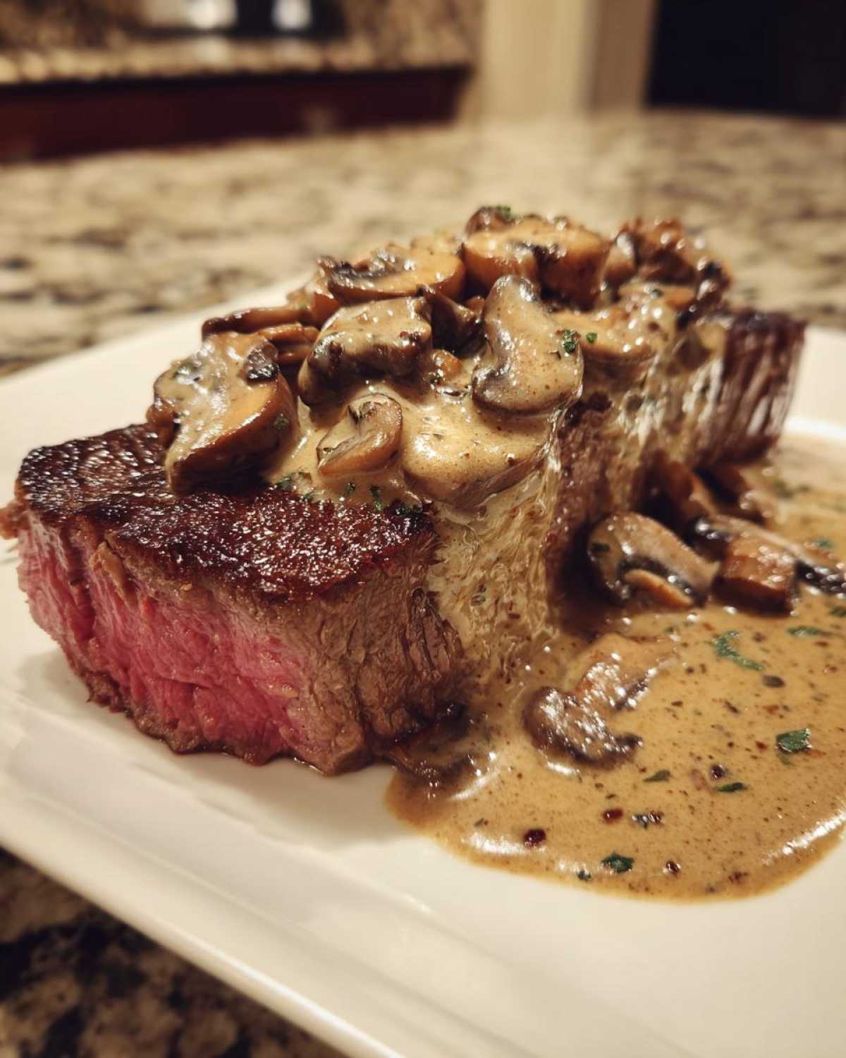 Close-up of a perfectly cooked medium-rare steak topped with creamy mushroom sauce, part of the Garlic Butter Steak with Creamy Mushroom Sauce recipe.