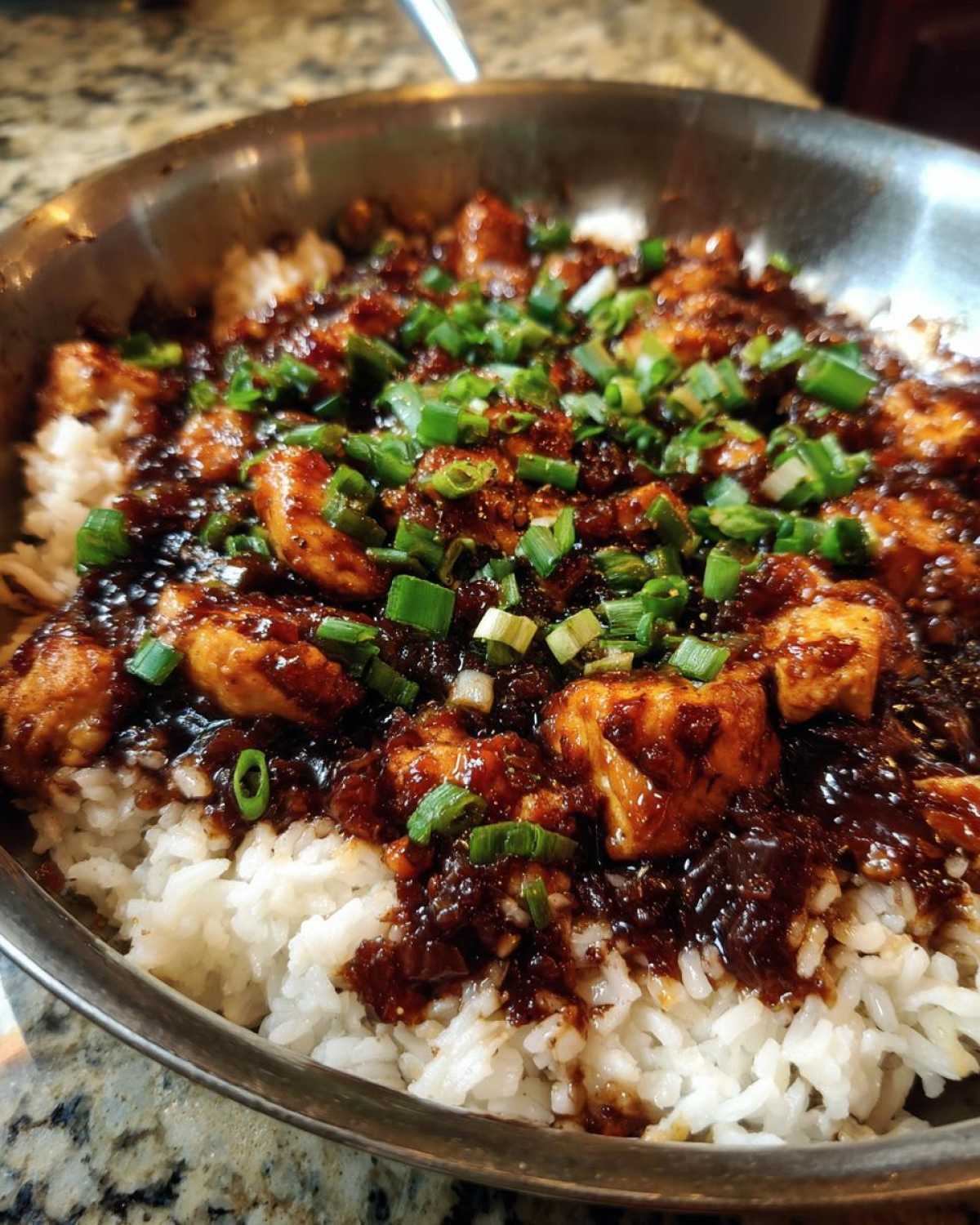 Close-up of Honey Garlic Chicken Skillet with Rice topped with fresh green onions.