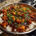 Close-up of Honey Garlic Chicken Skillet with Rice, featuring glazed chicken pieces over white rice topped with green onions.
