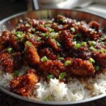 Close-up of glistening Honey Garlic Chicken Skillet pieces served over white rice and garnished with chopped green onions.