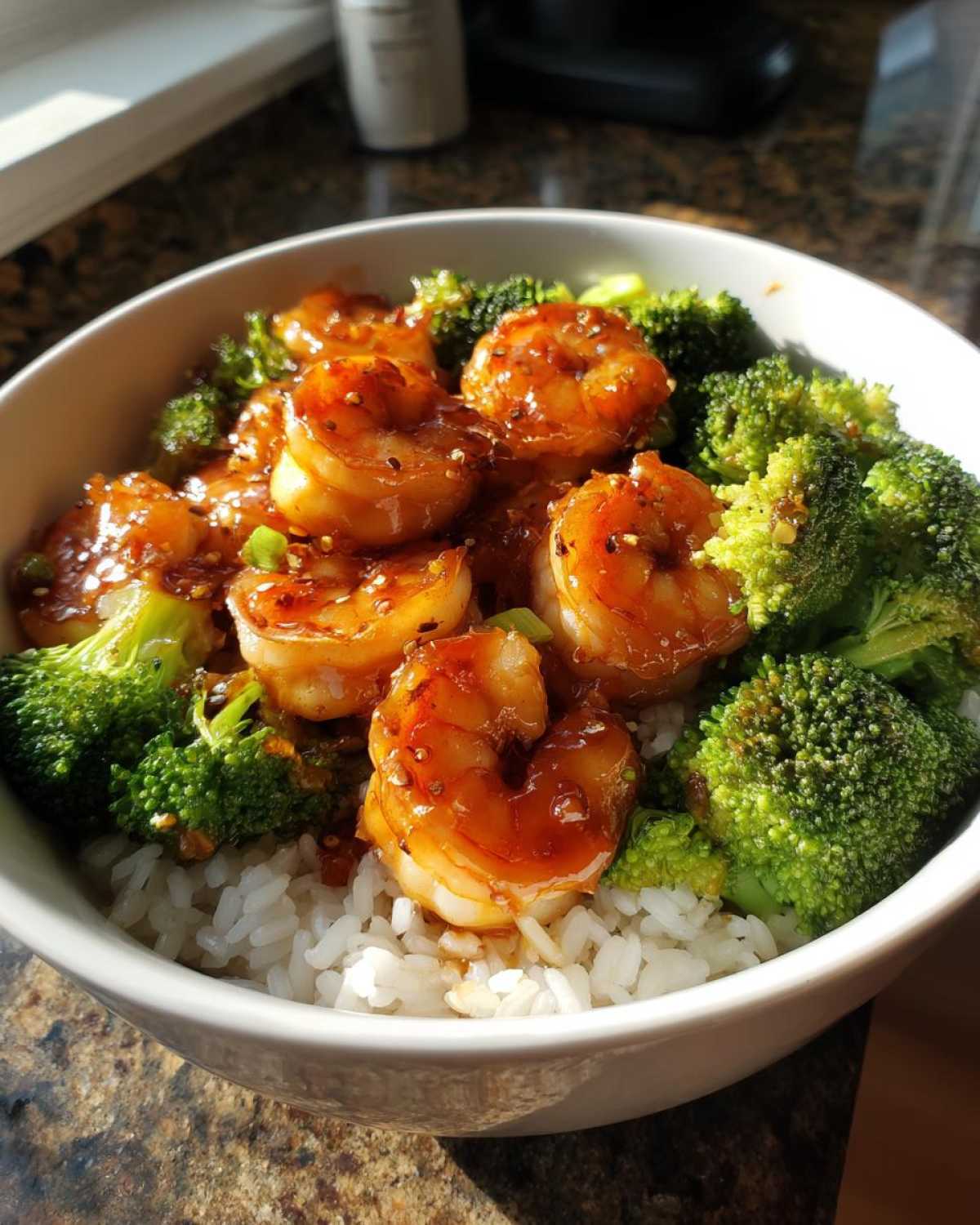Close-up of a Honey Garlic Shrimp Bowl Quick Dinner featuring glazed shrimp, bright green broccoli florets, and white rice in a bowl.