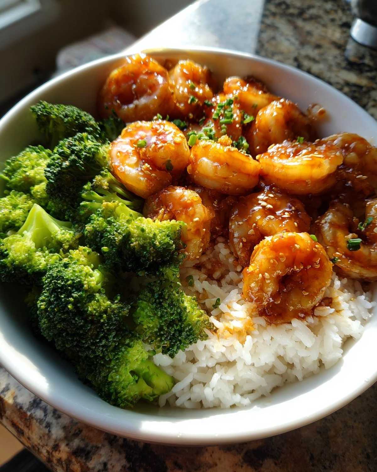 A close-up of a Honey Garlic Shrimp Bowl Quick Dinner featuring glazed shrimp, bright green broccoli, and white rice.