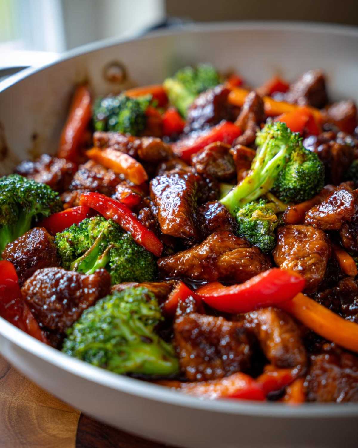 Close-up of glossy, glazed Honey Soy Chicken Skillet with vibrant broccoli, red peppers, and carrots in a white pan.