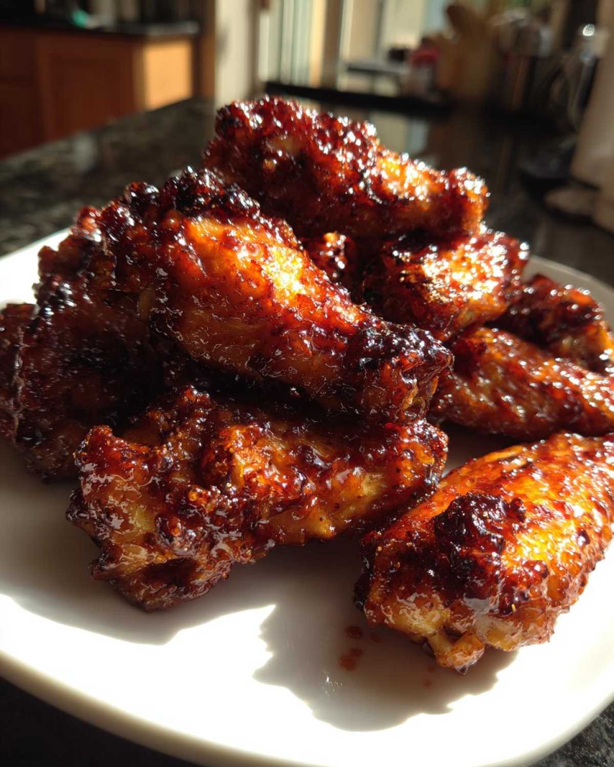 A pile of incredibly sticky and crispy Honey Sriracha Chicken Wings glistening under bright light.