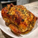 A whole Lemon Herb Roasted Chicken with incredibly crispy, golden-brown skin covered in herbs.