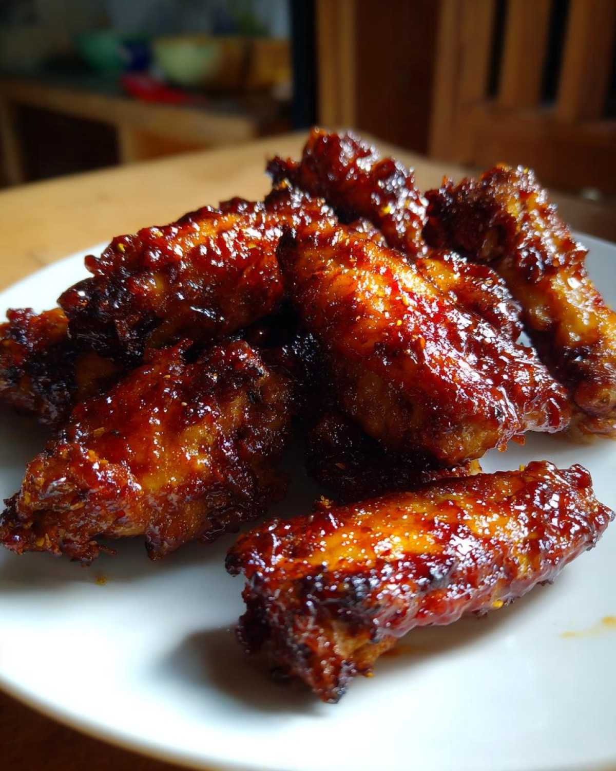 Close-up of several Sticky BBQ Chicken Wings Crispy Oven Style coated in a shiny, dark glaze.