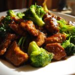 Close-up of pieces of chicken coated in glossy teriyaki sauce mixed with bright green broccoli florets in a Sticky Teriyaki Chicken Stir Fry Quick Meal.