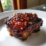 A close-up of one perfectly glazed Sticky Teriyaki Chicken Thighs with Garlic piece on a white plate.