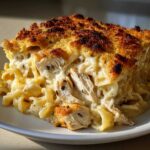 A close-up of a serving of Cheesy Baked Chicken Alfredo with Crispy Top showing creamy sauce and shredded chicken.