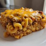 A hearty slice of Cheesy Ground Beef Pasta Bake with creamy sauce, topped with melted cheddar cheese.