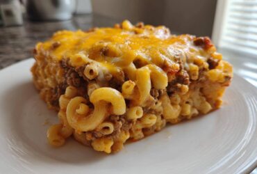 A hearty slice of Cheesy Ground Beef Pasta Bake with creamy sauce, topped with melted cheddar cheese.