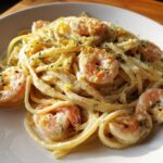 A close-up of a serving of Creamy Lemon Shrimp Pasta with Garlic Sauce, topped with lemon zest and herbs.