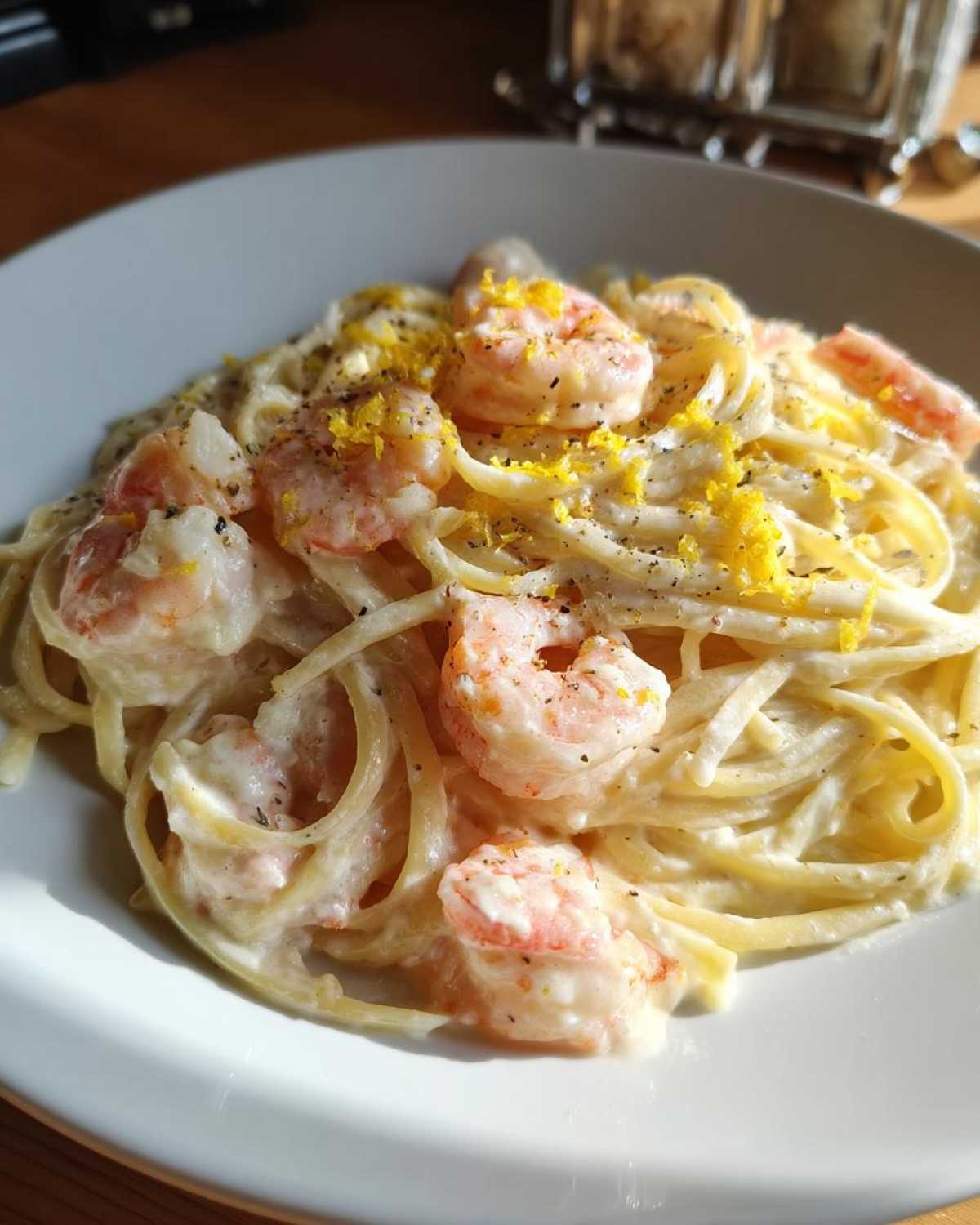 A close-up of Creamy Lemon Shrimp Pasta with Garlic Sauce, featuring linguine tossed in a rich white sauce, topped with pink shrimp and bright lemon zest.