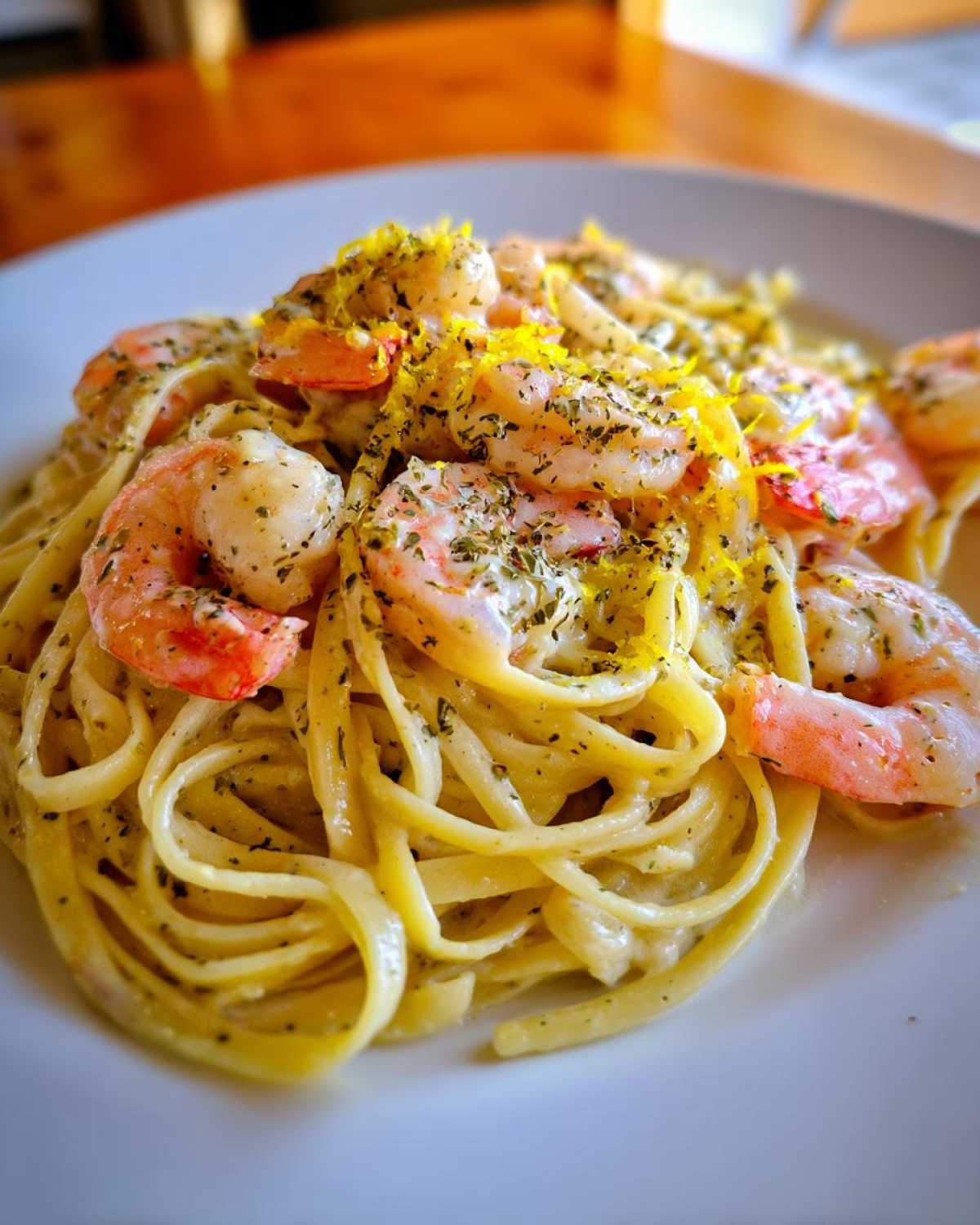 A close-up shot of Creamy Lemon Shrimp Pasta with Garlic Sauce, topped with bright lemon zest and herbs.