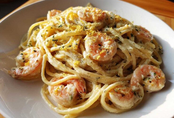 A close-up of a serving of Creamy Lemon Shrimp Pasta with Garlic Sauce, topped with lemon zest and herbs.