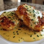 Two golden brown Crispy Parmesan Chicken Cutlets smothered in a rich, creamy sauce and topped with fresh parsley.