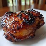Close-up of a perfectly cooked Honey Garlic Chicken Thighs with dark, glossy, crispy skin.