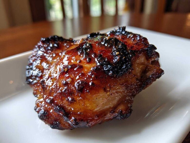 Close-up of a perfectly cooked Honey Garlic Chicken Thighs with dark, glossy, crispy skin.