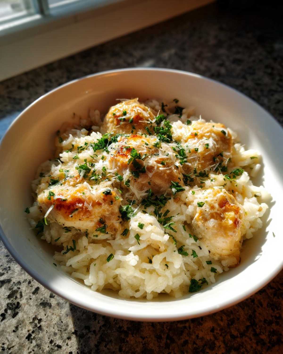A white bowl filled with Garlic Butter Chicken and Rice One Pot Dinner, topped with Parmesan and parsley.