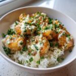 Close-up of a Garlic Butter Shrimp Rice Bowl topped with creamy garlic sauce and fresh parsley.