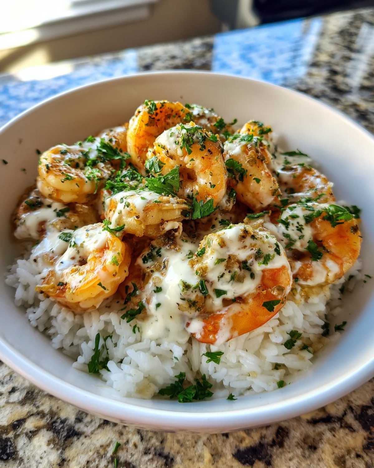Close-up of a Garlic Butter Shrimp Rice Bowl featuring plump shrimp drizzled with creamy garlic sauce and fresh parsley over white rice.