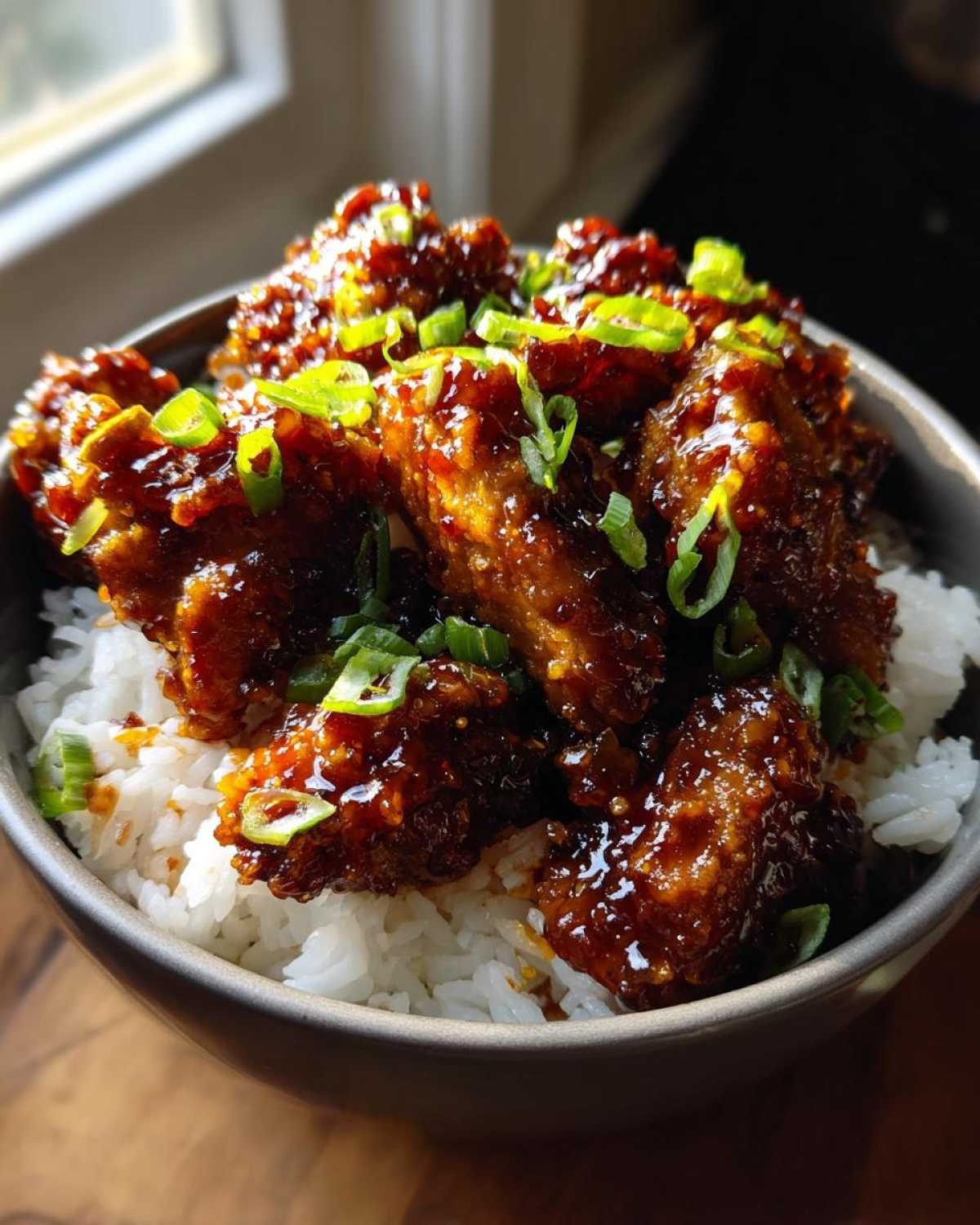 Close-up of Sticky Sweet Chili Chicken Skillet pieces coated in glossy sauce served over white rice and garnished with green onions.