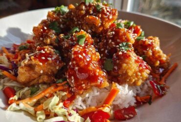 Close-up of a Sweet Chili Chicken Bowl featuring crispy chicken pieces glazed with sauce, served over rice and crunchy slaw.